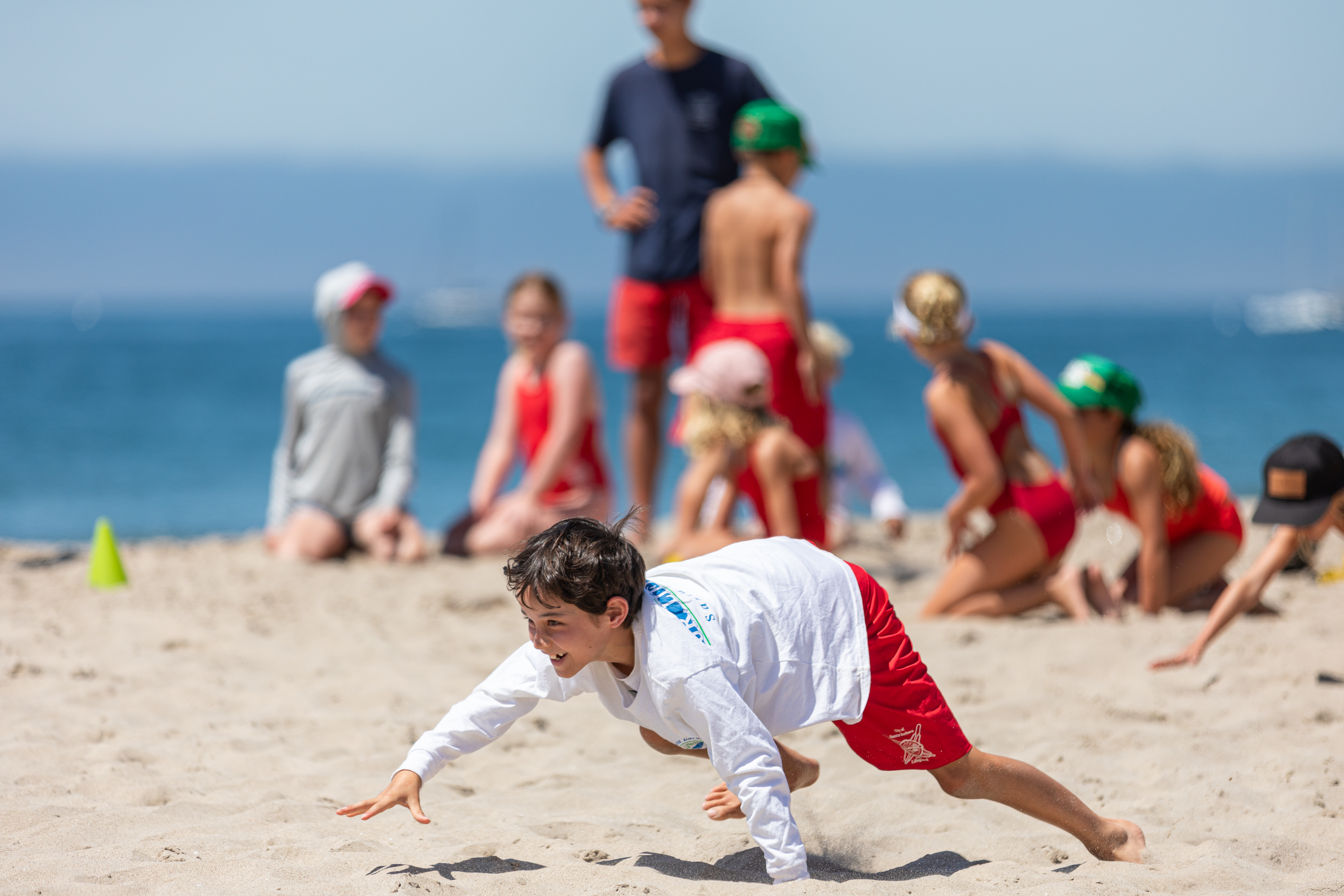Junior Lifeguard bear crawls across the sand in a relay competition