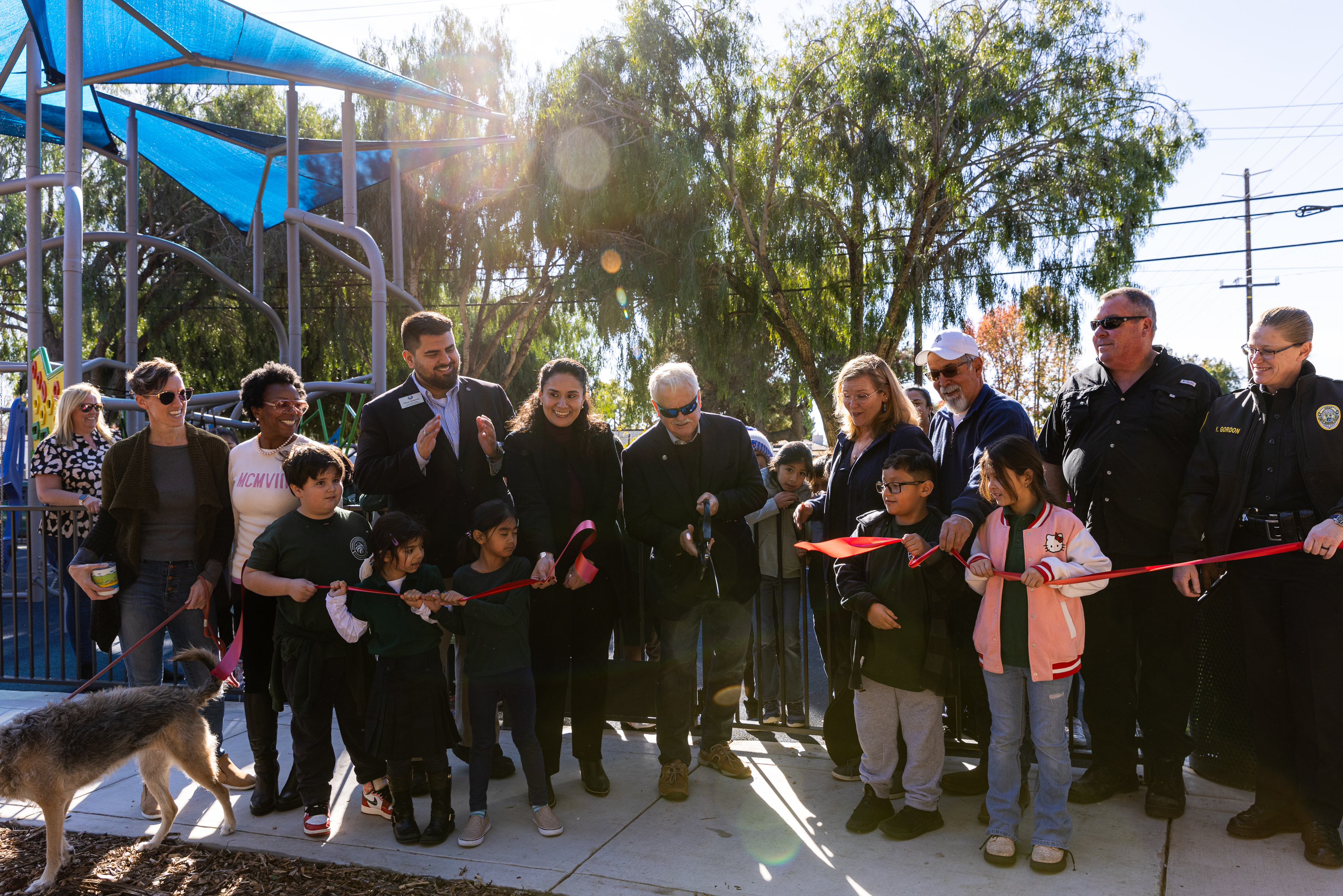 Community leaders and members cut a ribbon in front of a new playground at Eastside Park