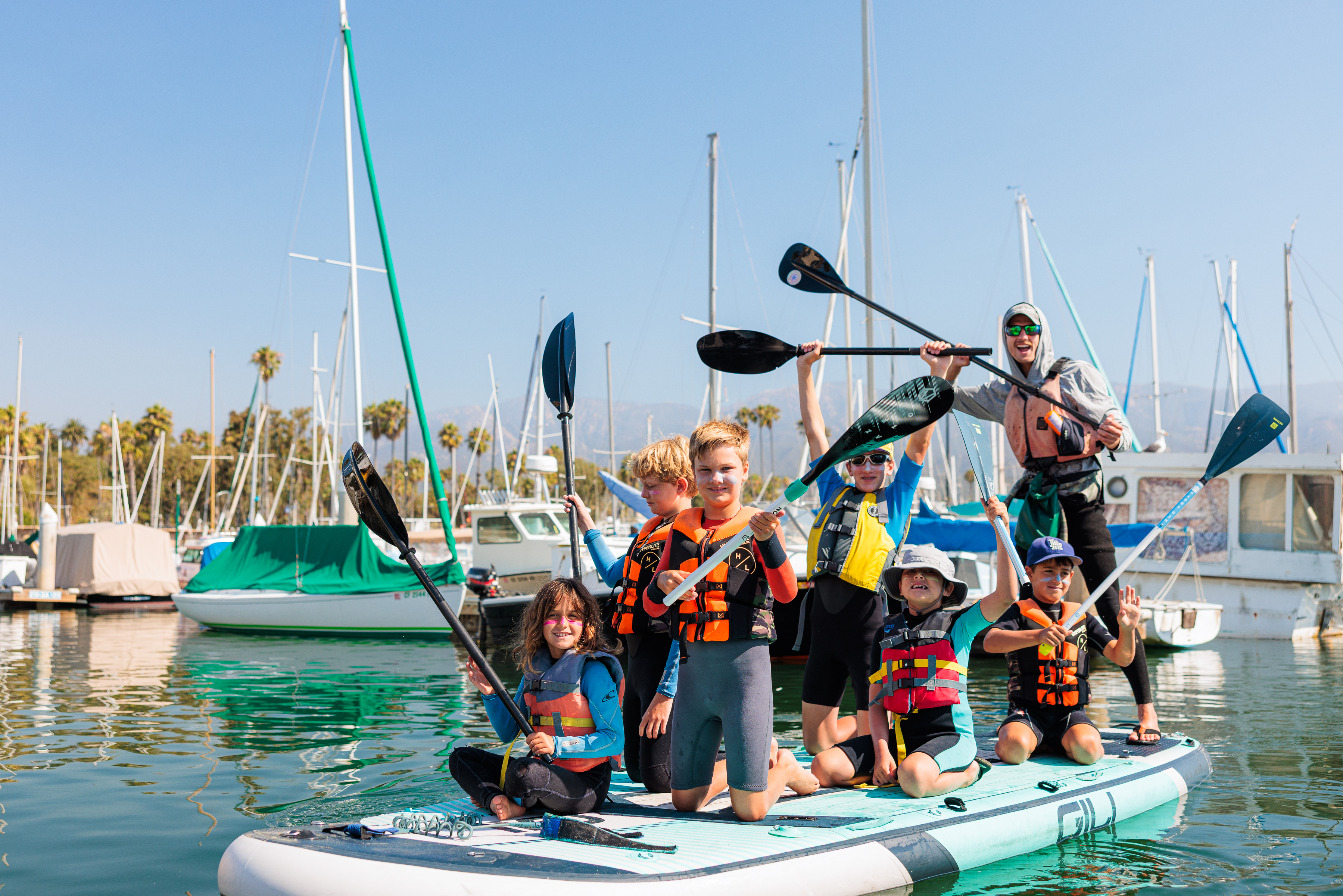 Children smile on a paddleboard 