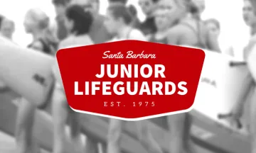 Kids with surfboards and Junior Lifeguards graphic in foreground