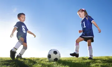 Two children playing soccer