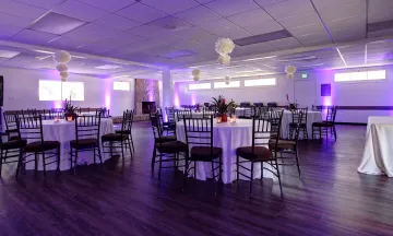 Interior of MacKenzie Center setup for an event with tables, chairs, and purple lighting