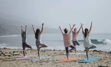 Stock image of a group of people taking a yoga class on a beach.