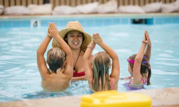 Children in pool following directions of swim instructor