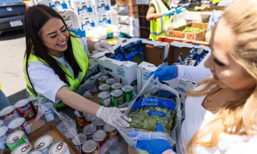 Volunteer wearing gloves laughing as they package and hand out food