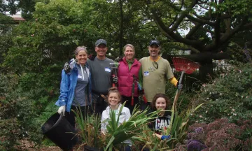 A group of volunteers pose for a picture in Alice Keck Park Memorial Garden with rakes in hand
