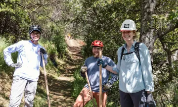 Three trail restoration volunteers smiling
