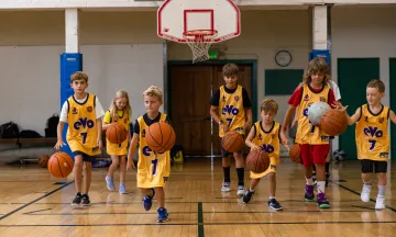 Kids dribbling basketballs on a basketball court.