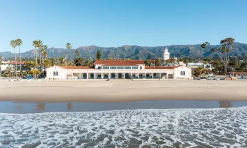 View of Cabrillo Pavilion with beach and ocean in the foreground and mountains in the background