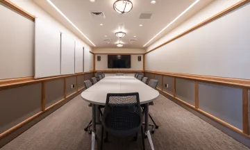 Cabrillo Pavilion conference room with a conference table and 10 chairs, featuring a television on the end wall and white boards on the side walls