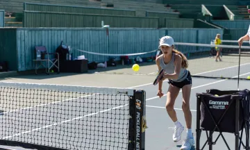 Camper hits a pickleball over the net with great focus