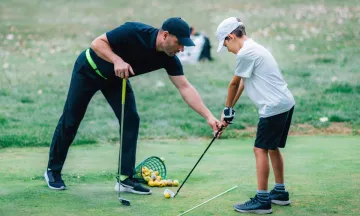 Young golfer is given tips on his swing by an instructor