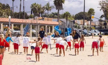 Junior Lifeguard campers do warm up drills in their uniforms