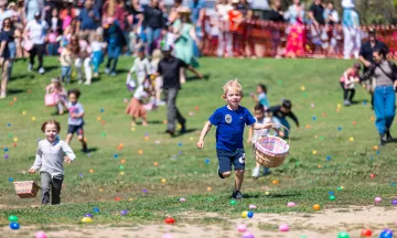 Children running on grass full of colorful plastic eggs