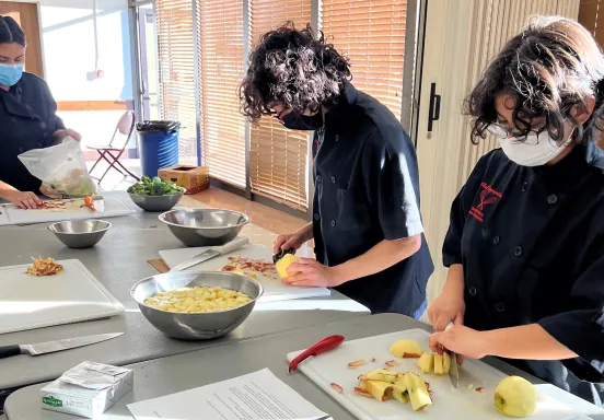 Three participants of the Chef Apprentice Program prep ingredients