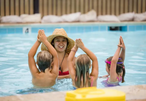 Children in pool following directions of swim instructor