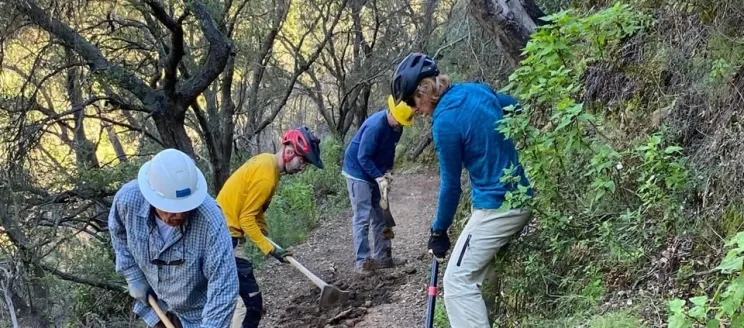 Volunteers work on repairing a damaged trail