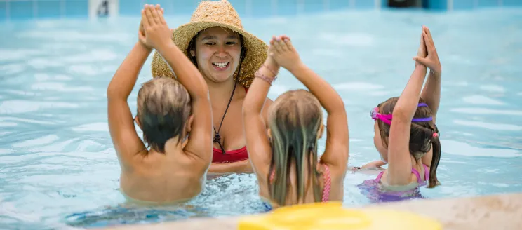 Children in pool following directions of swim instructor