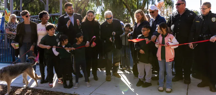 Community leaders and members cut a ribbon in front of a new playground at Eastside Park