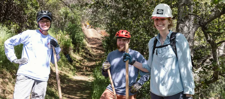 Three trail restoration volunteers smiling