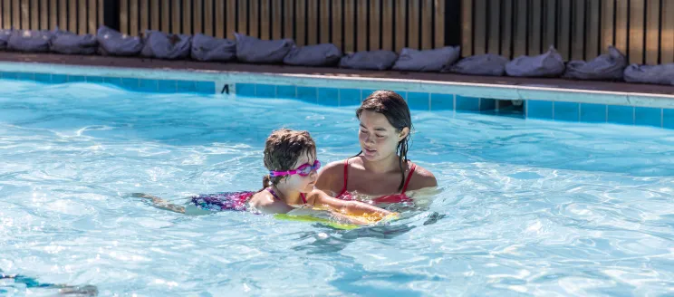 Swim instructor guides a young swimmer as they learn to kick