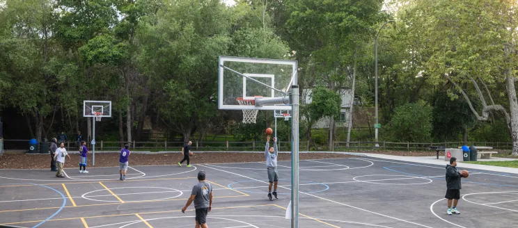 Community members play basketball on the new court at Bohnett Park