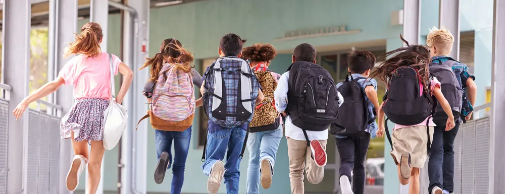 Several children with backpacks walking at school