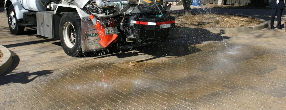 A water truck sprays water on permeable pavers at Oak Park