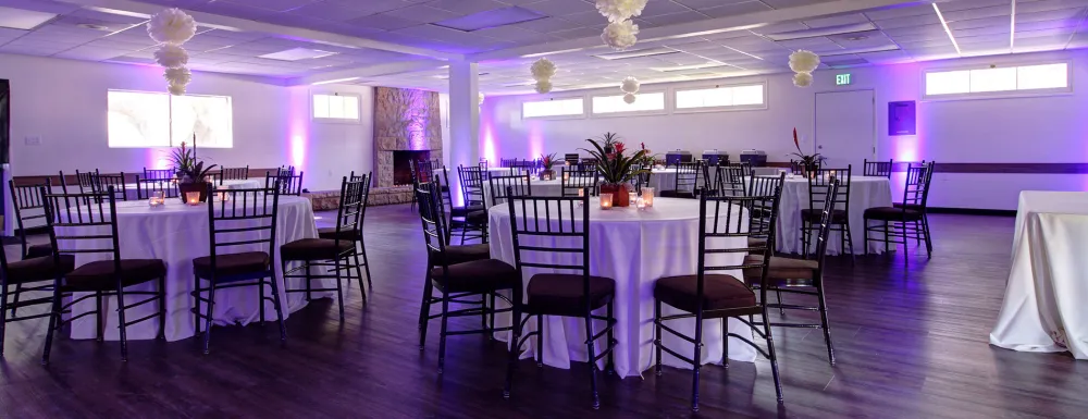 Interior of MacKenzie Center setup for an event with tables, chairs, and purple lighting