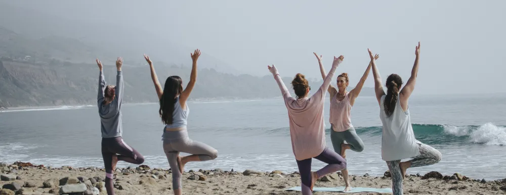 Stock image of a group of people taking a yoga class on a beach.