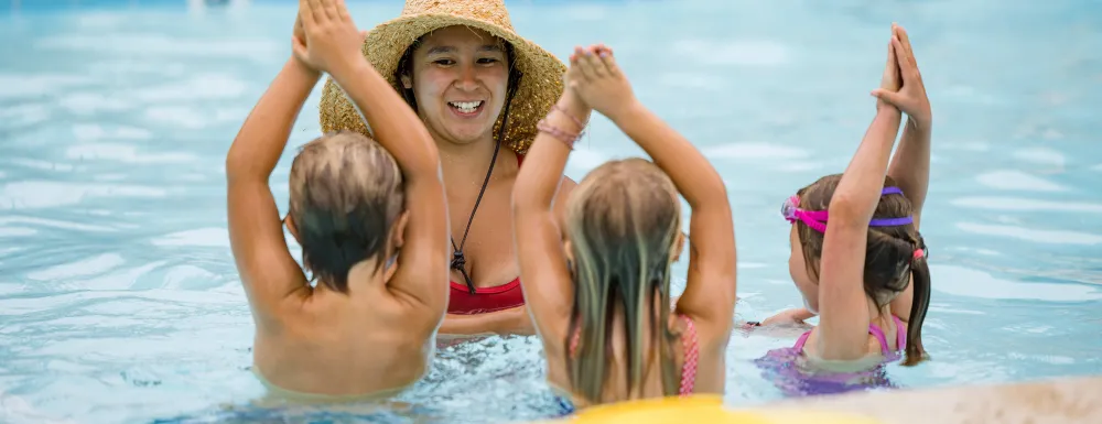 Children in pool following directions of swim instructor