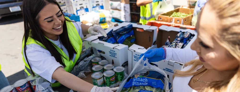 Volunteer wearing gloves laughing as they package and hand out food