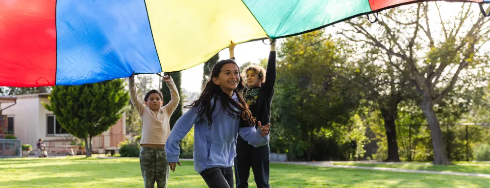 Students play with a giant parachute at the Recreation Afterschool Program