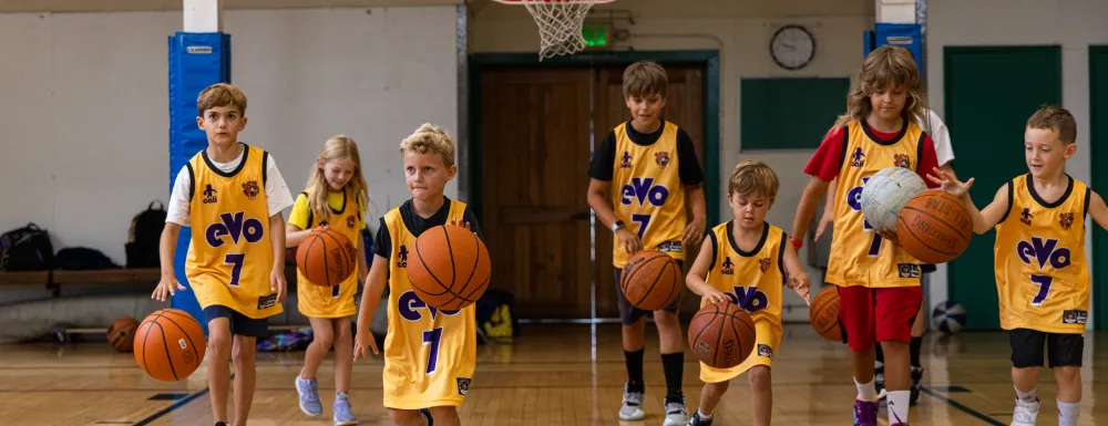 Kids dribbling basketballs on a basketball court.