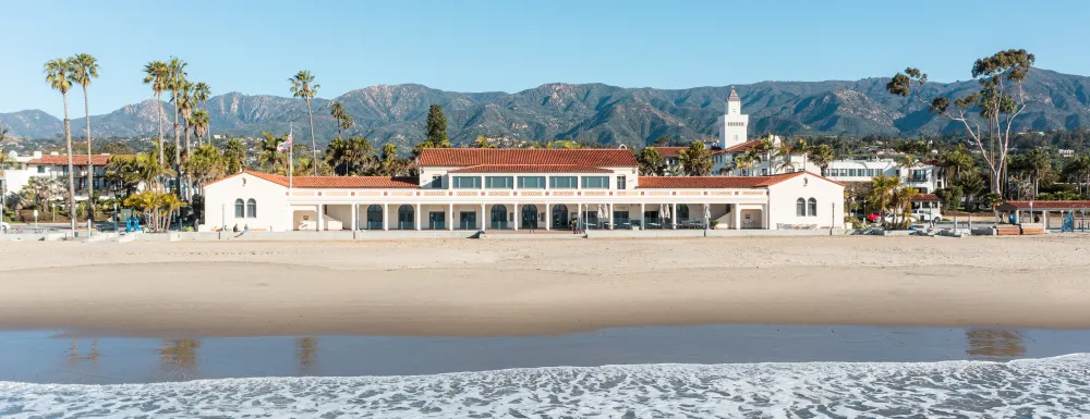 View of Cabrillo Pavilion with beach and ocean in the foreground and mountains in the background