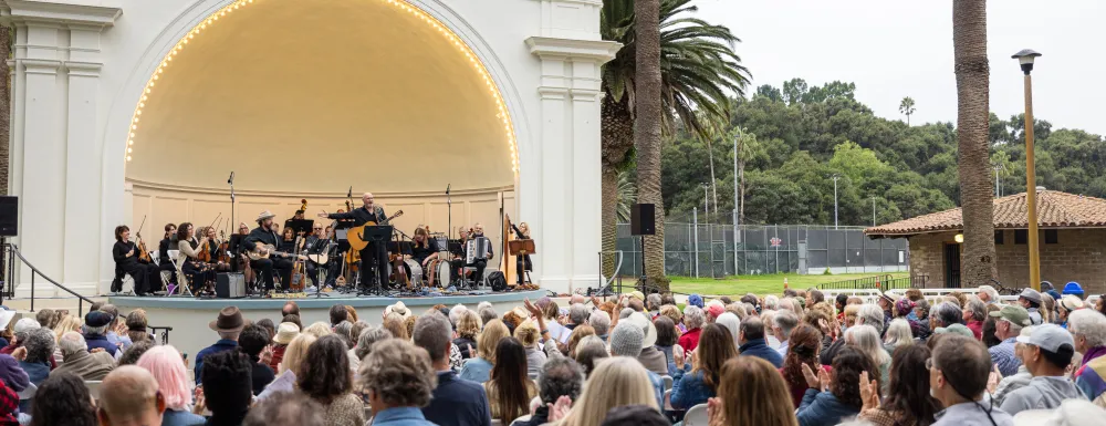Folk Orchestra performing in front of a large crowd at the Plaza del Mar Band Shell