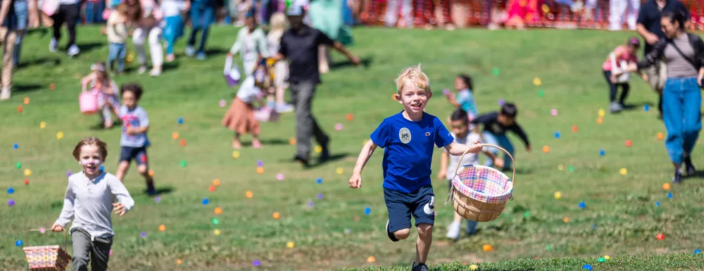 Children running on grass full of colorful plastic eggs