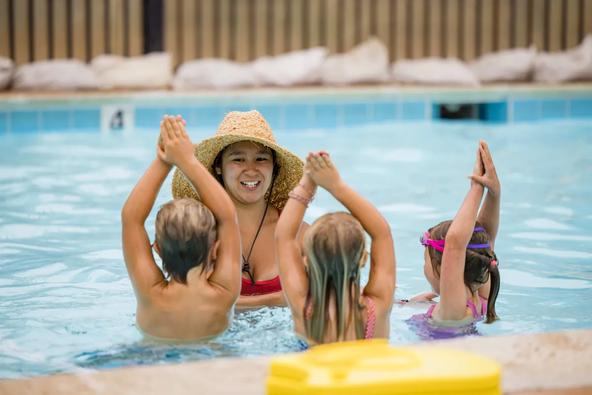 Children in pool following directions of swim instructor