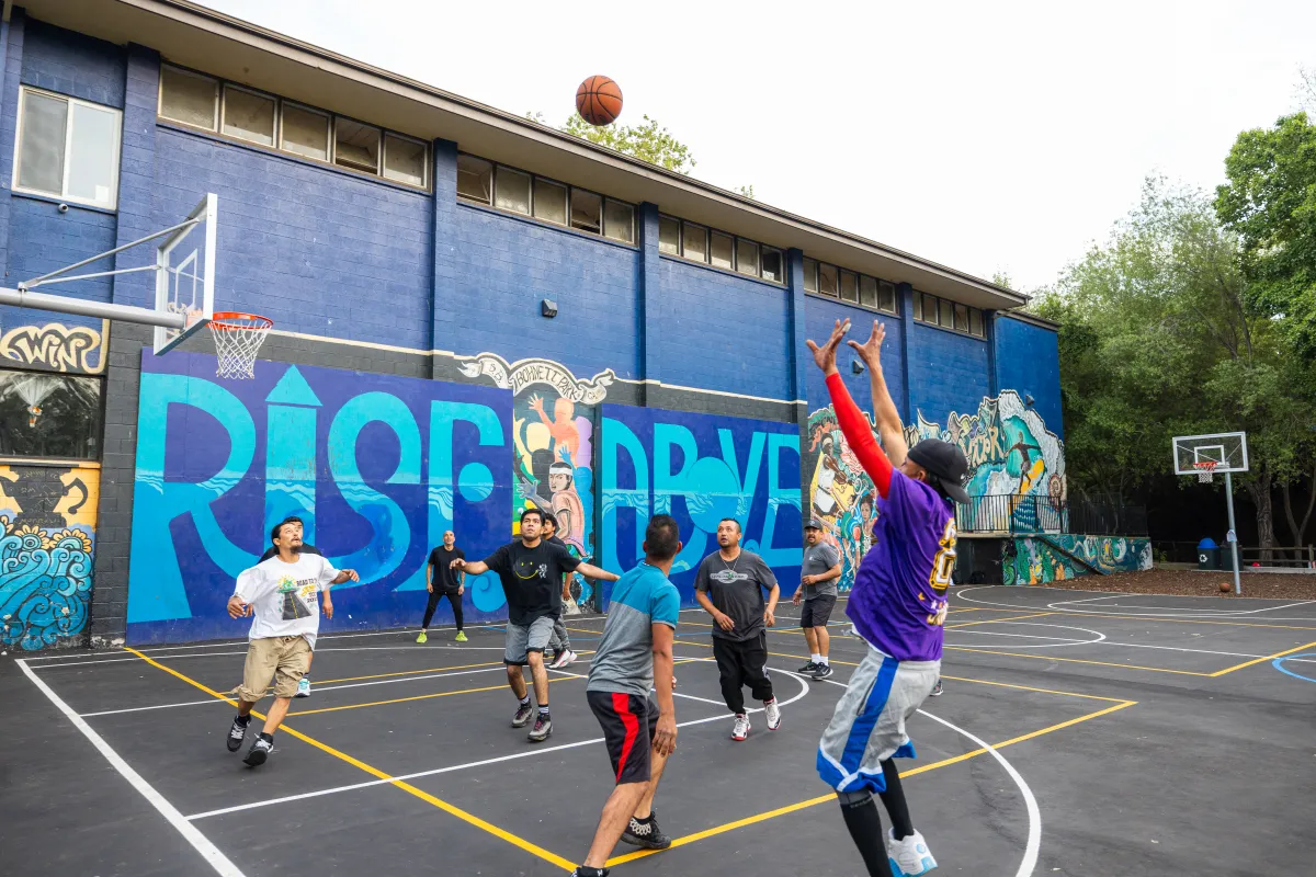 Community members play basketball on the new court at Bohnett Park