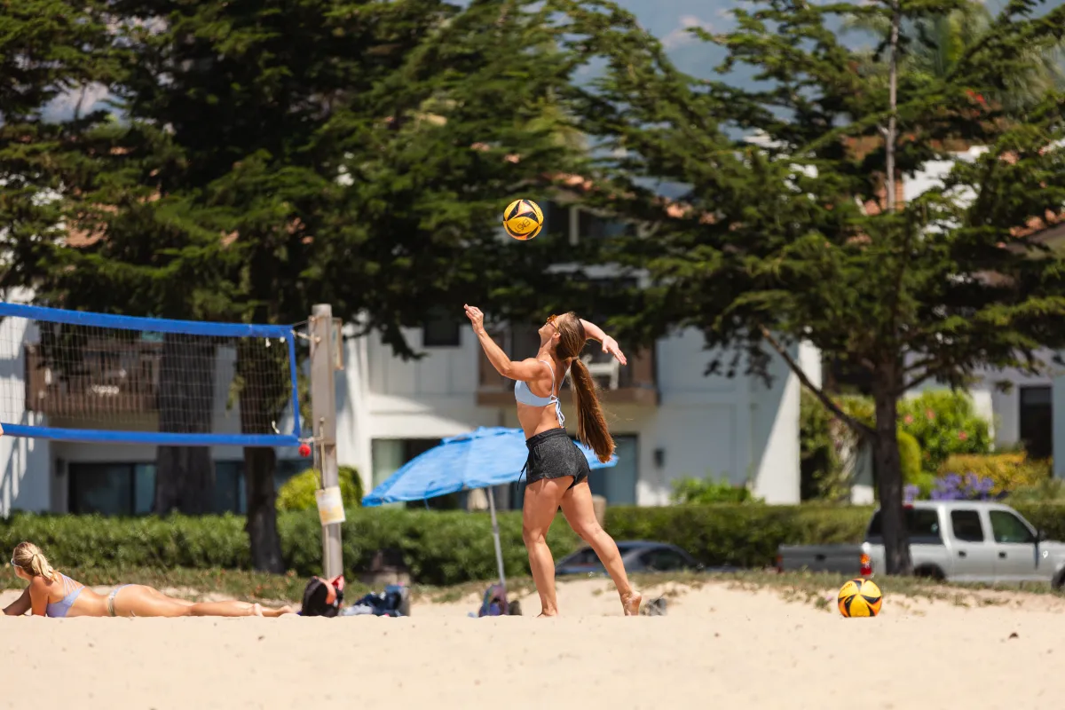 Community member serves a beach volleyball at East Beach