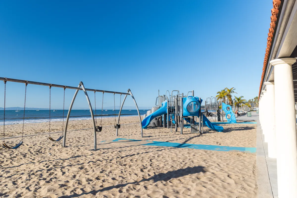 Swing set and playground on sand at East Beach Park
