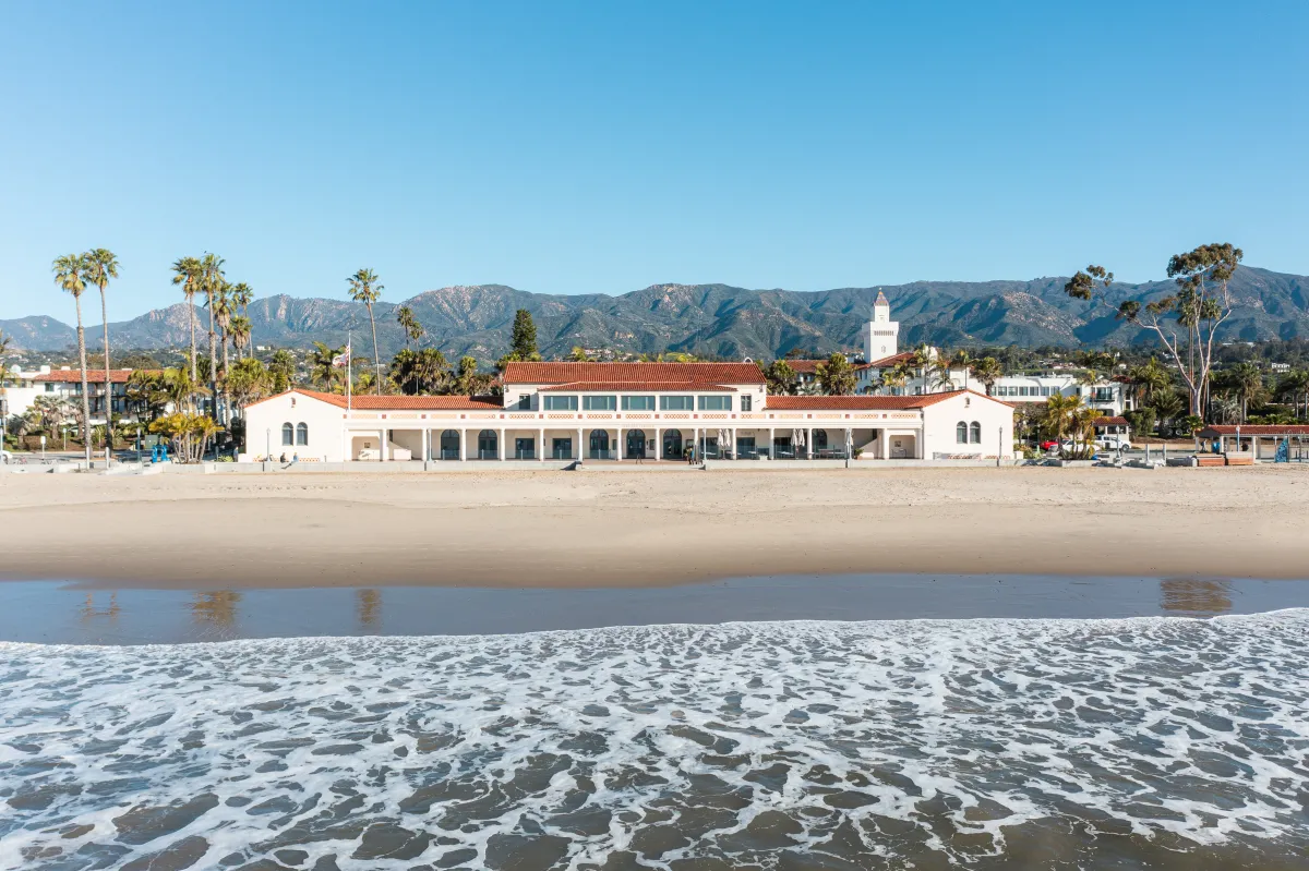 View of Cabrillo Pavilion with beach and ocean in the foreground and mountains in the background