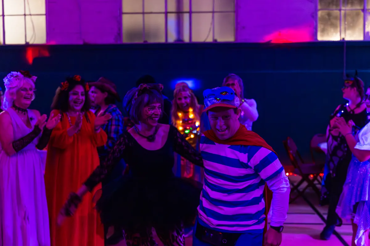 Dance attendees dressed in Halloween costumes laugh and dance