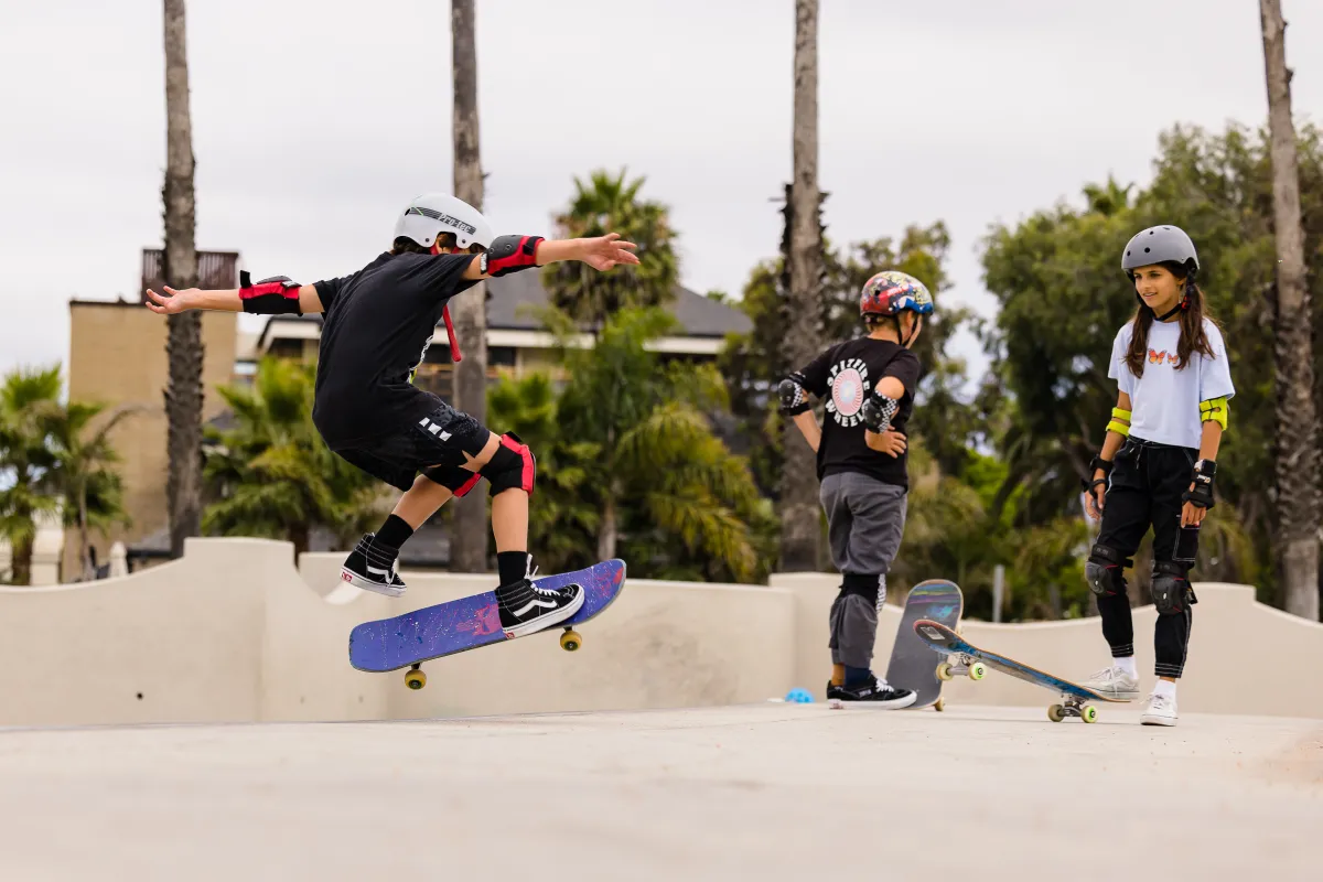 Camper does a jump at Skate Camp with another camper looking on