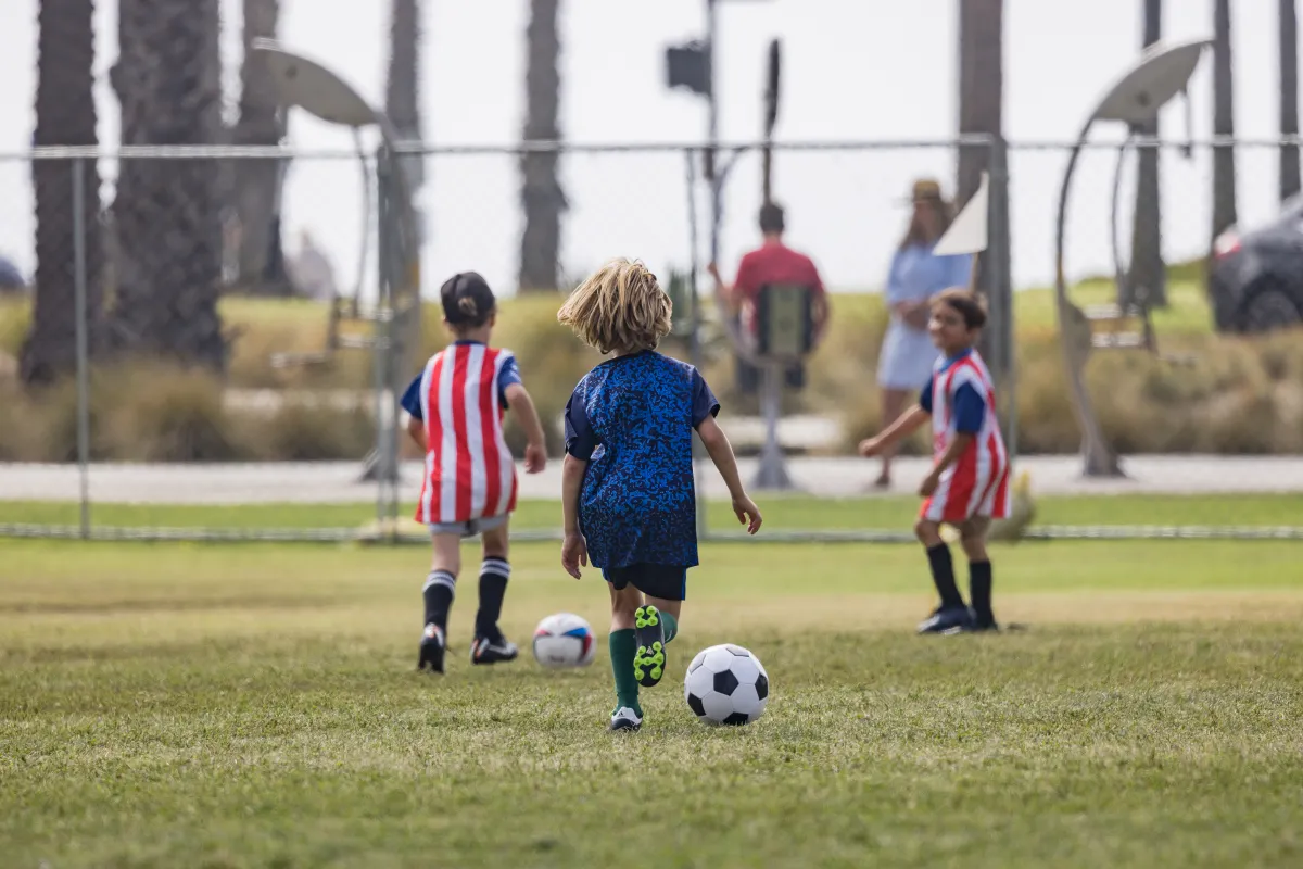 Camper dribbles a soccer ball away from the camera