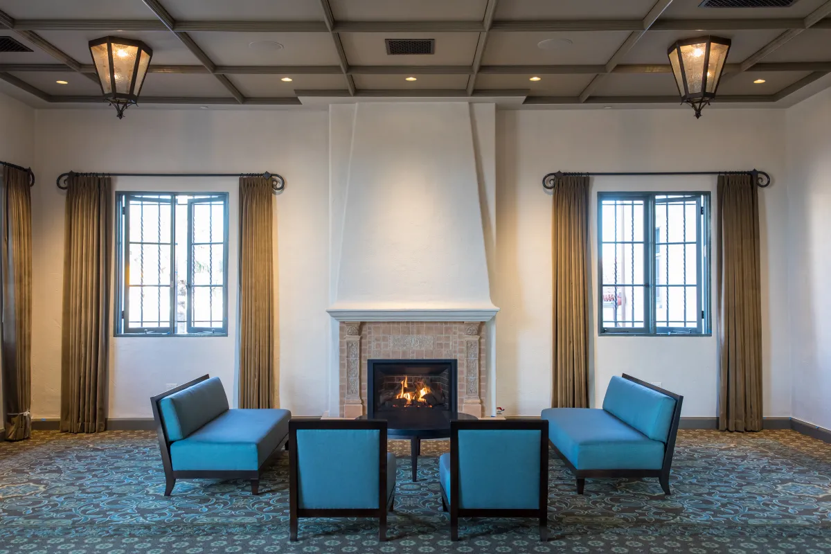 Photo of the entry lounge at the Cabrillo Pavilion Event Center, with plush blue chairs set up in front of the fireplace. 