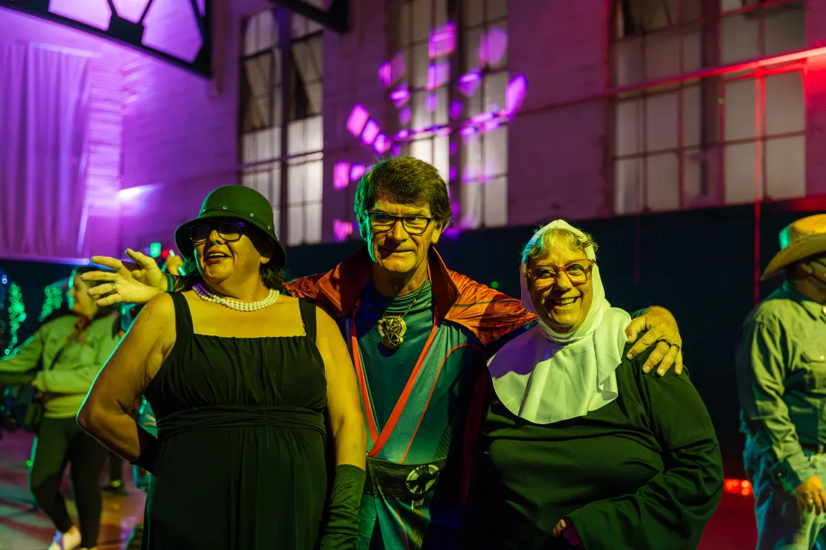 Three participants smiling at the camera in their Halloween costumes