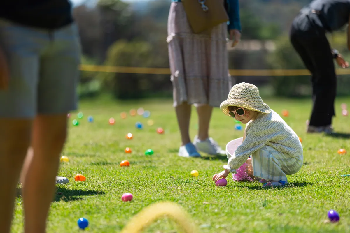 Child picking up a colorful plastic egg