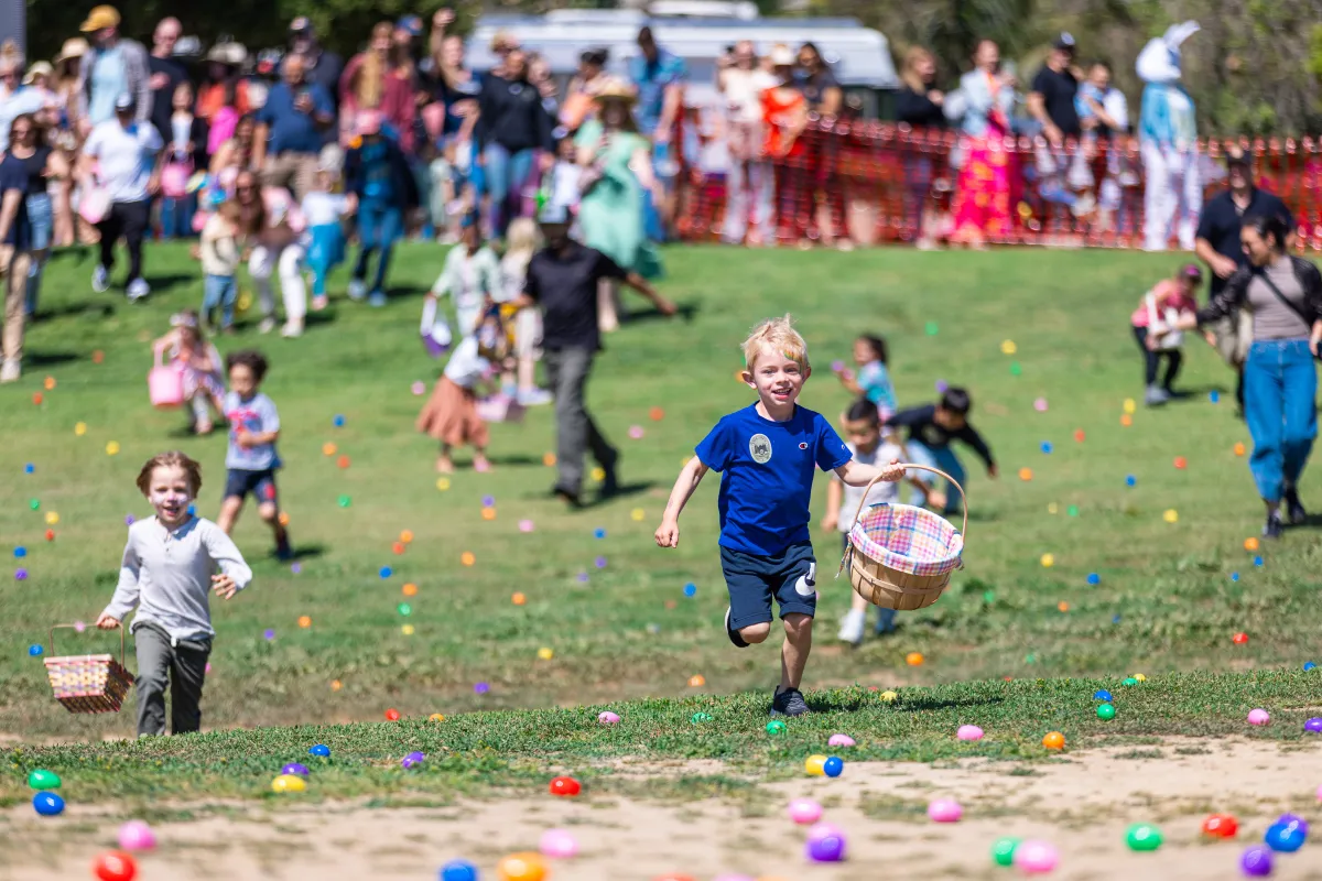 Children running on grass full of colorful plastic eggs