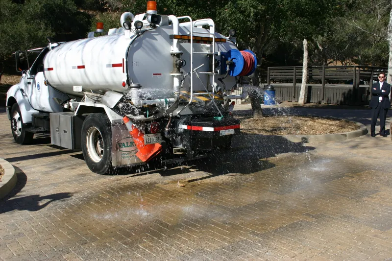 A water truck sprays water on permeable pavers at Oak Park